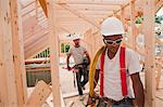 Carpenters holding power cord and level at construction site