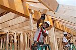 Charpentier en utilisant un sawzall sur les planches du toit d'une maison en construction