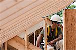 Hispanic carpenter holding a tape measure on upper floor at a house under construction