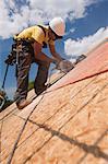 Carpenter using a circular saw on the roof panel at a house under construction site