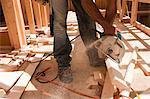 Hispanic carpenter using circular saw on board at a construction site