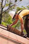 Hispanic carpenter pulling sheathing at a house under construction