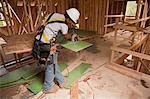 Carpenter using a circular saw on exterior wall sheathing in a house under construction