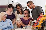 Engineering students examining completed machined part with professor