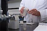 Scientist pouring liquid from a container to a small vial in the laboratory of water treatment plant