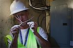 Cable installer preparing to splice wire at power panel in the cellar of a house