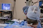 Docteur regardant au microscope pendant une intervention chirurgicale avec technicien chirurgicale en prenant le prochain instrument
