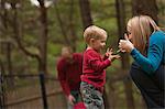 Femme signant le mot « Play » en American Sign Language, tout en communiquant avec son fils dans un parc