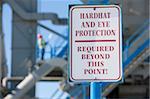 Warnung Schild mit der Aufschrift ""Bauarbeiterhelm und Auge Schutz erforderlich Beyond This Point"" bei einer Industrieanlage