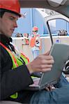 Engineer using a laptop in truck with an another engineer inspecting site