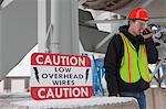 Engineer talking on a walkie-talkie beside a warning sign