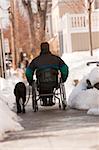 Femme avec une sclérose en plaques dans un fauteuil roulant avec un chien d'assistance dans la neige de l'hiver