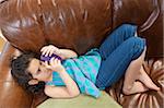 Hispanische Mädchen auf einer Couch liegen und Blick auf eine SMS-Nachricht auf einem Mobiltelefon
