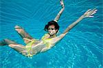Young woman swimming underwater in swimming pool