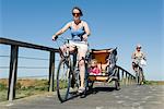 Multi-generation family enjoying bicycle ride, children sitting in bicycle trailer