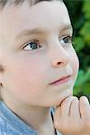 Boy with hand under chin, looking up in thought