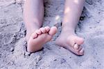 Legs of little girl in sand, low section