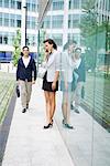 Woman talking on cell phone outside of office building, man walking by