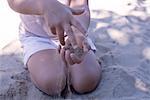 Little girl playing with sand in hands, mid section