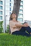 Woman sitting in grass looking up in thought