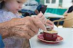 Fille de bambin aider grand-mère mélanger la tasse de café, recadrée