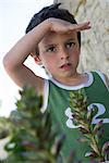 Boy looking at something out of frame, shading eyes with hand