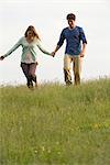 Young couple walking on meadow holding hands