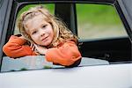 Little girl leaning out car window, portrait