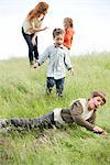 Boys playing in field, mother and sister in background