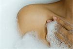 Woman taking bubble bath, cropped