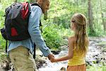 Father and young daughter hiking together in woods