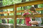 Baby girl and older sister looking over railing of bridge