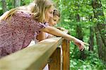 Mother and young daughter looking over railing together