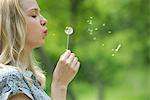 Young woman blowing dandelion flower