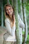 Woman leaning against tree trunk, portrait