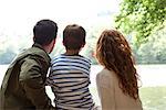 Family sitting together looking at lake, rear view