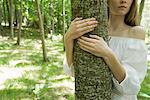 Jeune femme étreignant arbre, recadrée