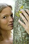 Young woman hugging tree, portrait