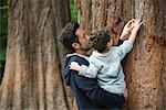 Father and young son touching tree bark