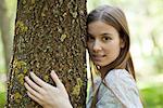 Junge Frau knuddeln Baum, portrait