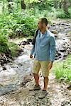 Man hiking along stream in woods