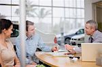 Car salesman giving papers to couple