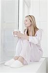 Woman having cup of coffee in pajamas