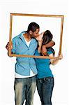 Mixed race couple kissing inside picture frame against white background