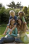 Two happy women with two children on blanket outdoors