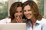 Two happy women using laptop