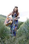 Young woman with guitar in corn field