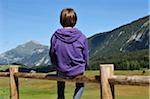 Back View of Boy Sitting on Wooden Fence, Glieres Plateau, Alps, France