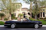 Side view of a open roof car in front of villa