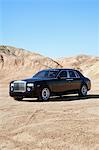 Rolls Royce parked on unpaved road with clear sky